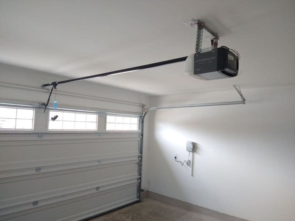 Garage interior with automatic door opener and white garage door, bright lighting.