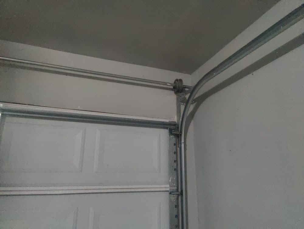 Garage door mechanism with tracks and pulley in a residential setting.