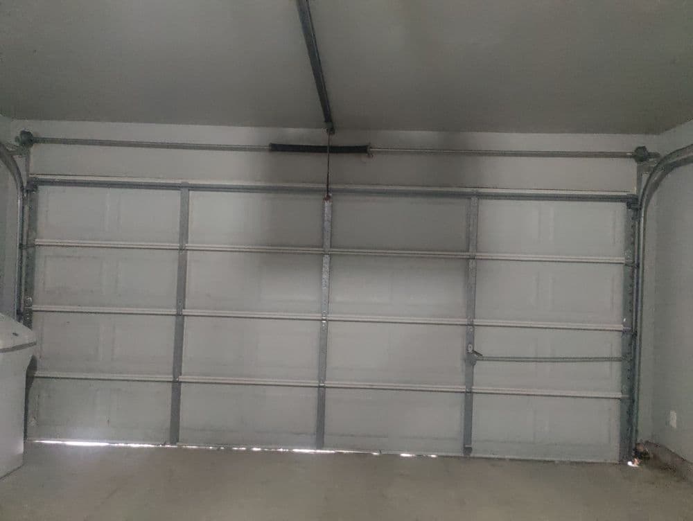 Interior of a garage with a white, raised panel garage door and concrete floor.
