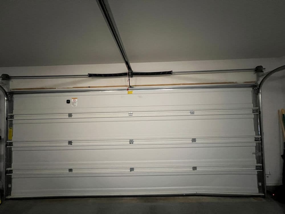 White garage door in a well-lit garage with metal tracks and clean floor.