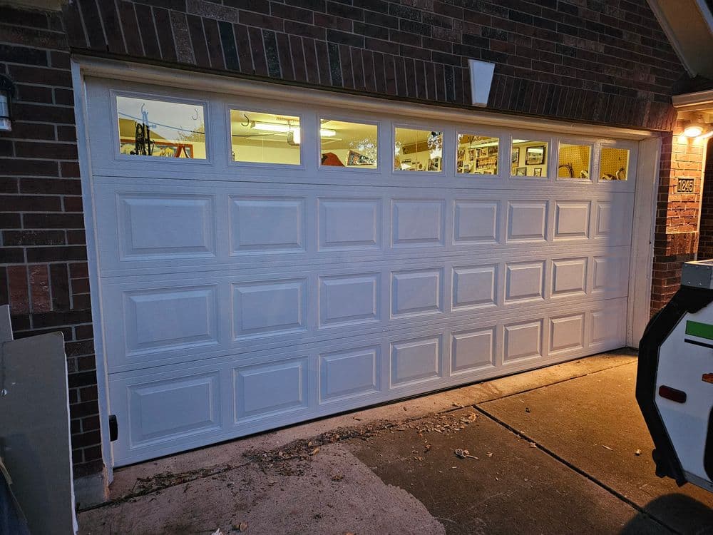 White garage door with windows, showcasing interior lighting and garage space.