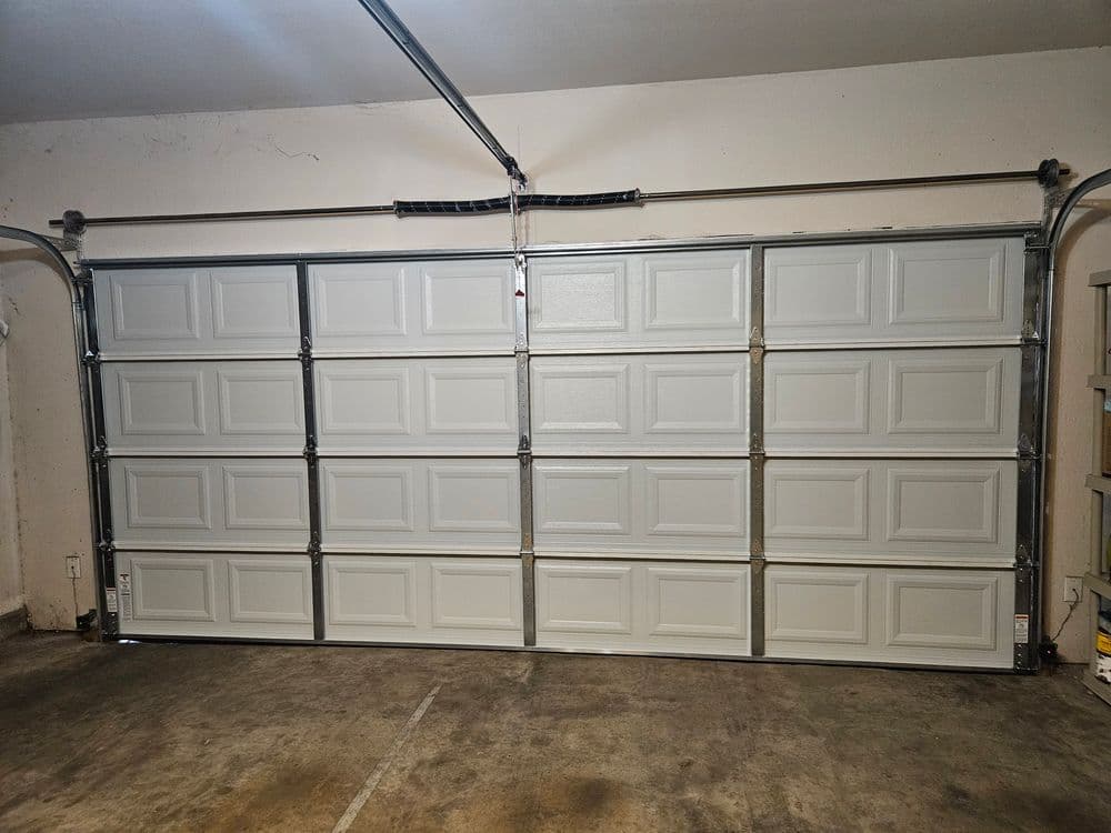 White sectional garage door in a spacious garage interior with concrete flooring.