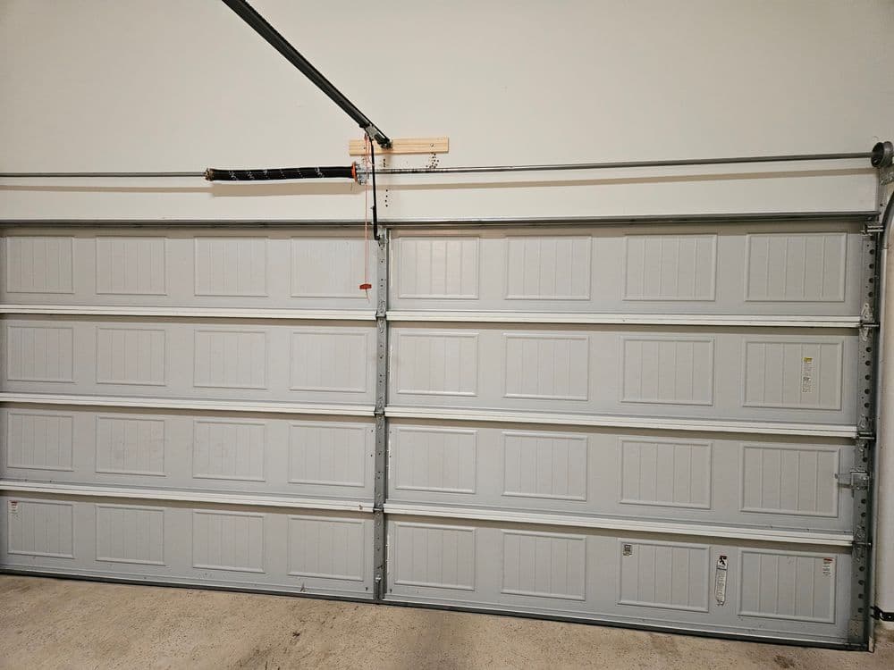 White sectional garage door with panels and a vertical track mechanism.
