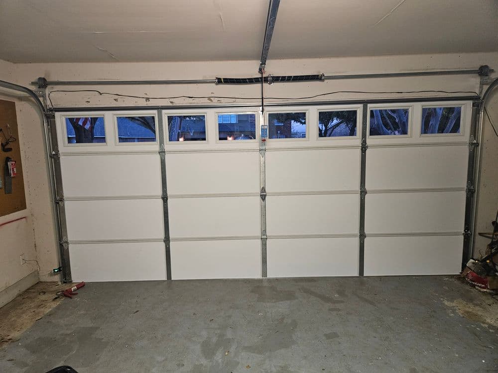 White garage doors with windows in a spacious garage interior.