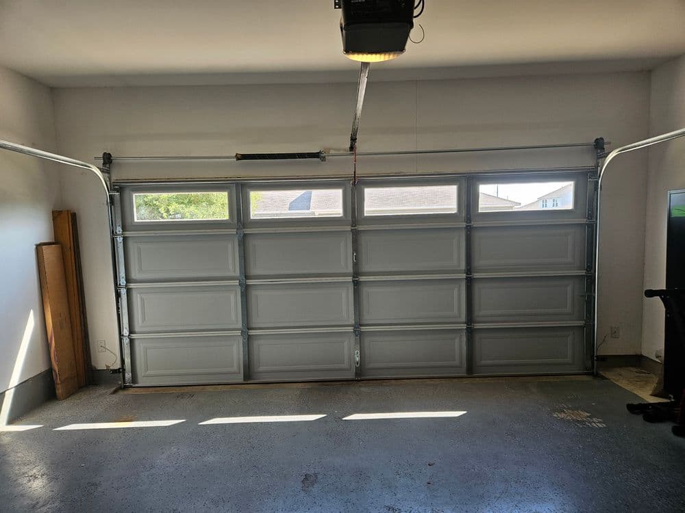 Interior view of a clean garage with a closed sectional garage door and natural light.